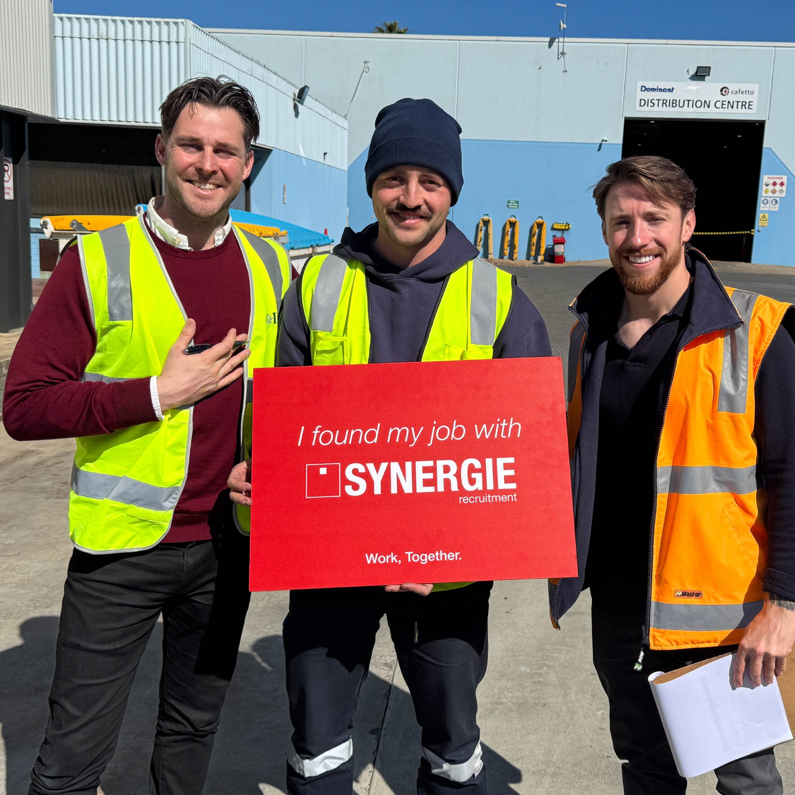 Synergie team members with a successful job candidate outside a distribution centre